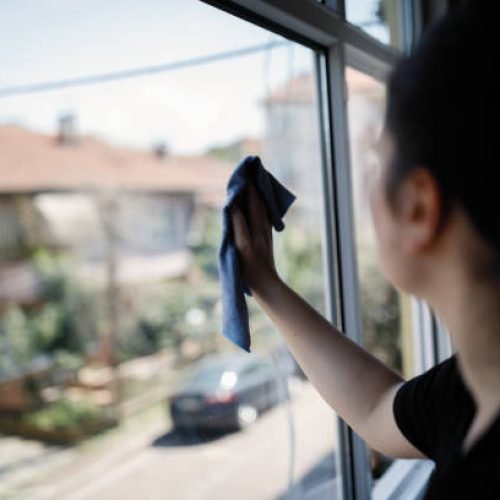Yong woman cleaning window