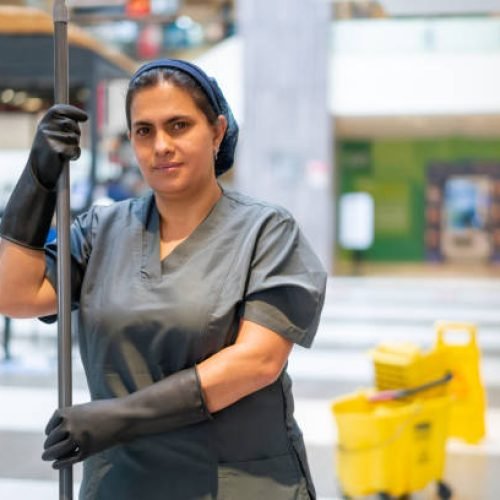Portrait of a Latin American cleaning lady mopping the floor while working at a shopping mall and looking at the camera smiling