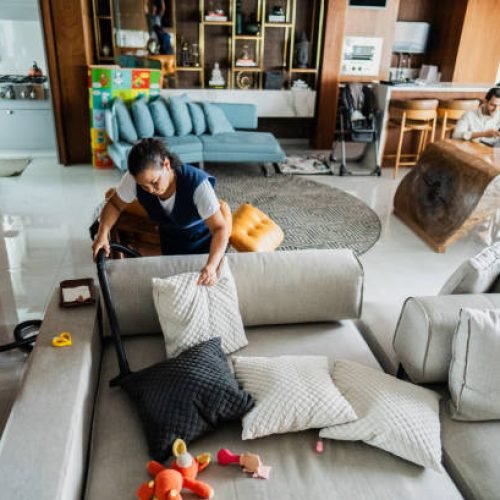 Housekeeper vacuuming sofa in a house
