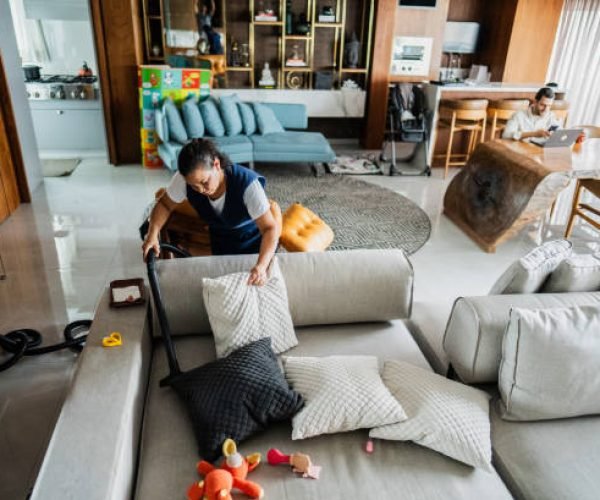 Housekeeper vacuuming sofa in a house